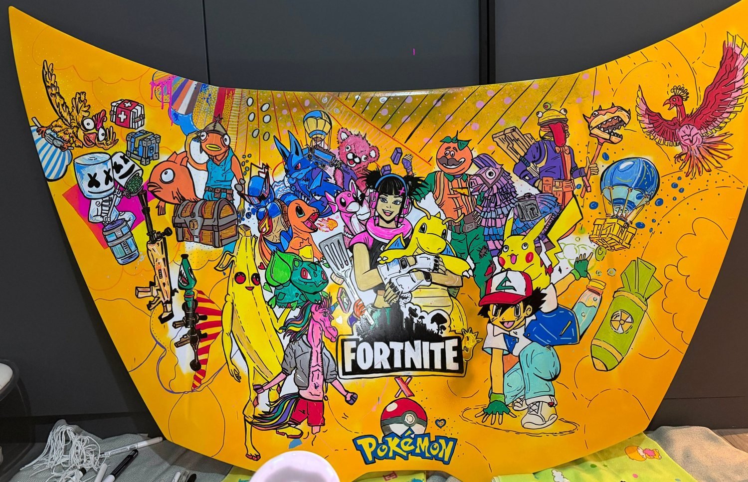 Hand-painted yellow car bonnet covered in Fortnite and Pokémon characters, painted by Oana Cocindau